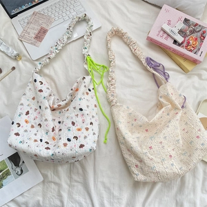 Détail de sacs sous le bras en toile avec gaufrage cartoon et accents de cordon coloré
