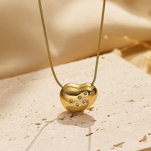 Elegant gold titanium heart necklace with zircon inlay on minimalist beige silk background
