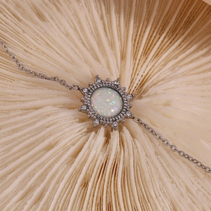 Silver bracelet with a sun pendant, white opal, and zircons on a natural background
