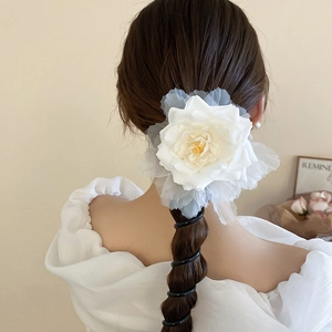 Détail d'un chouchou fleur blanche sur une tresse avec des pétales en organza doux