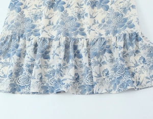 Detail of blue floral and bird print on lightweight fabric with ruffled hemline