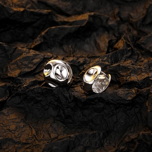 Detail view of irregular silver ball earrings with polished finish on black background