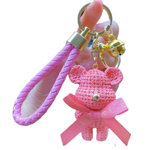 Pink resin bear keychain with knitted texture and gold ring shown held by a hand