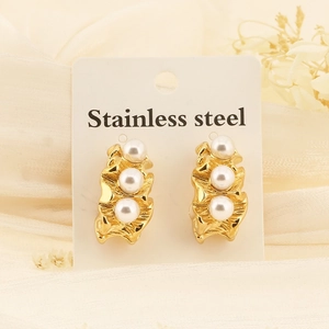 Détail de boucles d'oreilles dorées en acier plissé avec trois perles blanches