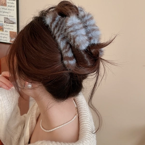 Détail de la pince à cheveux en peluche rayée sur modèle pour un style d'hiver