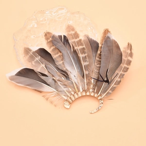 Macro detail of vintage peacock feather ear cuff with golden wavy metal base