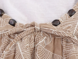 Macro view of embroidery details with dark bead accents and ties on khaki cotton linen fabric
