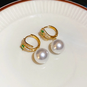Close-up of gold earrings with green stones and elegant white hanging pearl detail