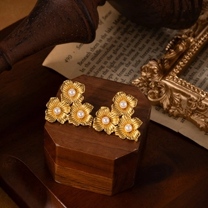 Elegant gold flower stud earrings with three petals and white pearls on vintage stand