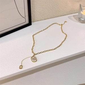 Gros plan d'un collier doré avec pendentif H en cristal et incrustation de nacre blanche