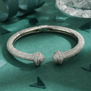 Silver geometric open cuff bracelet with pavé diamonds and spherical ends on green background