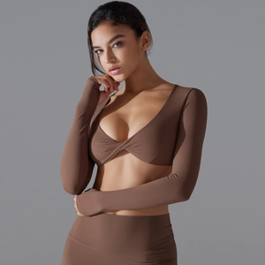 Dettaglio del crop top da yoga marrone scuro a maniche lunghe con nodo a incrocio e scollo a V