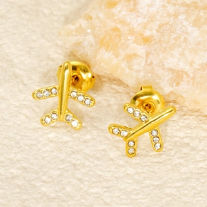 Close-up of golden airplane-shaped stainless steel earrings with sparkling zircon wings