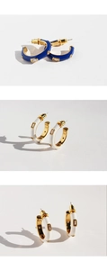 Macro detail of C-shaped hoop earrings with white enamel and blue zircon stones