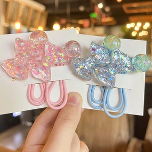 Detail of sequin-filled resin bow hair ties in pink and blue on display card