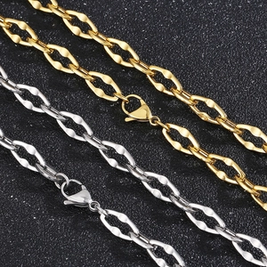 Close-up of gold and silver titanium steel lip link chains with lobster clasps on black surface