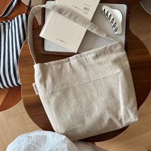 Detail shot of a beige linen tote bag with 'simple wish' label on a vintage wooden table