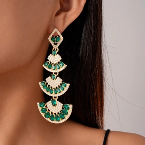 Close-up of emerald green drop earrings with vintage fan design and gold setting