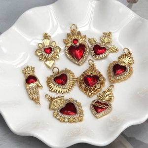 Detail of red heart charms with gold finish and rhinestones in a white ceramic bowl