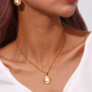 Detailed view of a gold sunflower pendant necklace and matching earrings on a model