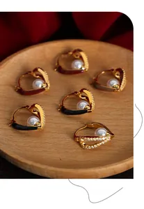 Detail of heart-shaped gold earring with colored enamel, zircon pavé and white pearl