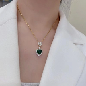18K gold heart necklace with emerald gemstone and zircon stones on a female model