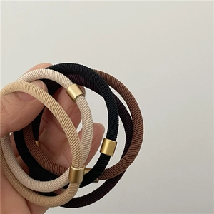 Close-up of elastic hair bands in beige and brown tones with gold metal buckles