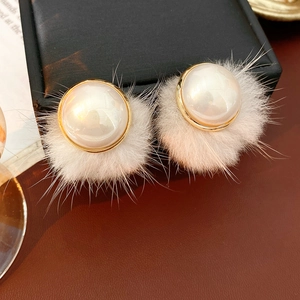 Macro shot of a vintage pearl earring with soft white fur trim and golden metal edges