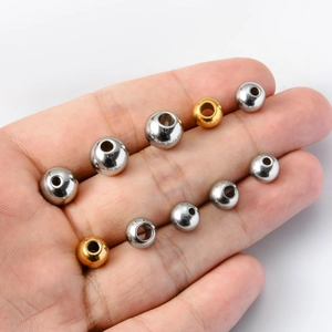 Polished gold and silver stainless steel loose spacer beads held in hand for DIY jewelry