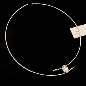 Macro shot of a silver choker featuring an oval crystal and punk spike accents