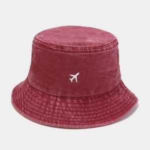 Détail du chapeau bob en coton délavé bordeaux avec broderie d'avion blanc élégante