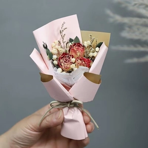 Close-up of mini bouquet with red dried roses and white gypsophila in pink wrapping