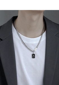 Close-up of men's silver Cuban chain necklace featuring a black rectangular pendant