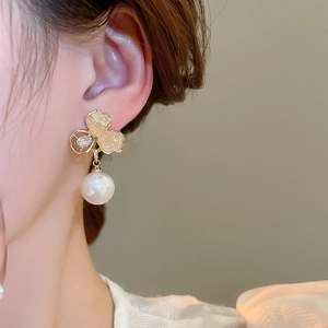 Gros plan de boucles d'oreilles fleur avec cristaux et une grande perle blanche