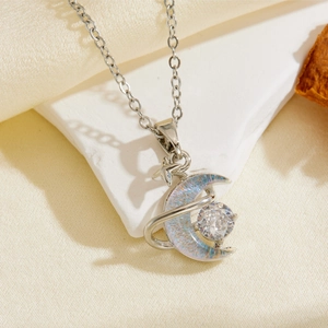 Detail of silver crescent moon and star pendant with sparkling crystals on white stone