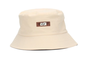 Detailed view of beige bucket hat with a brown leather patch and stitched brim texture
