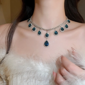 Close-up of elegant silver necklace featuring deep blue teardrop gems and sparkling diamonds