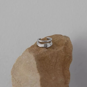 Minimalist silver double-layered ear cuff with polished finish on a natural stone base