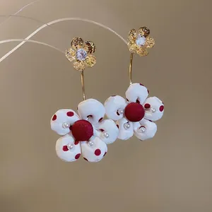 Floral stud earrings with gold petals, red polka dot fabric, and pearl accents