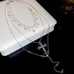 Macro detail of silver layered necklace with sparkling cross and star pendants