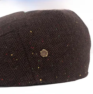 Close-up of brown herringbone wool tweed newsboy cap with colorful specks and W metal badge