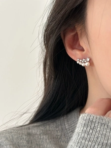 Close-up of elegant silver stud earrings with gradient pearls and cubic zirconia on model