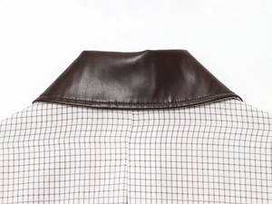 Détail d'une veste à carreaux bleus et blancs avec col en cuir marron contrastant