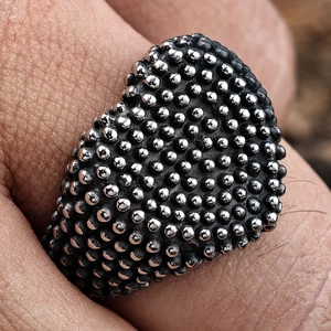 Macro shot of silver heart ring with textured beaded finish on finger detail