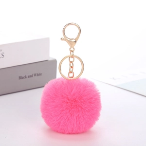 Detailed close-up of a pink faux rabbit fur pompom keychain with a gold metal ring fastener