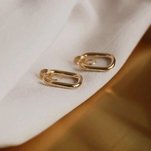 Close-up of golden oval link clip-on earrings with polished metallic mirror finish