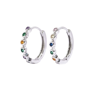 Macro detail of silver hoop earrings set with vibrant multi-colored gemstones