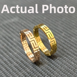 Close-up of rose gold and gold titanium rings with Greek meander cutout patterns