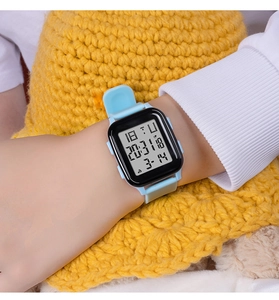 Close-up of blue silicone strap and rectangular black digital watch face on a wrist