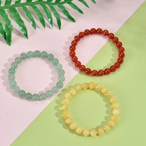 Detailed view of 8mm green, red, and yellow natural stone beaded stretch bracelets